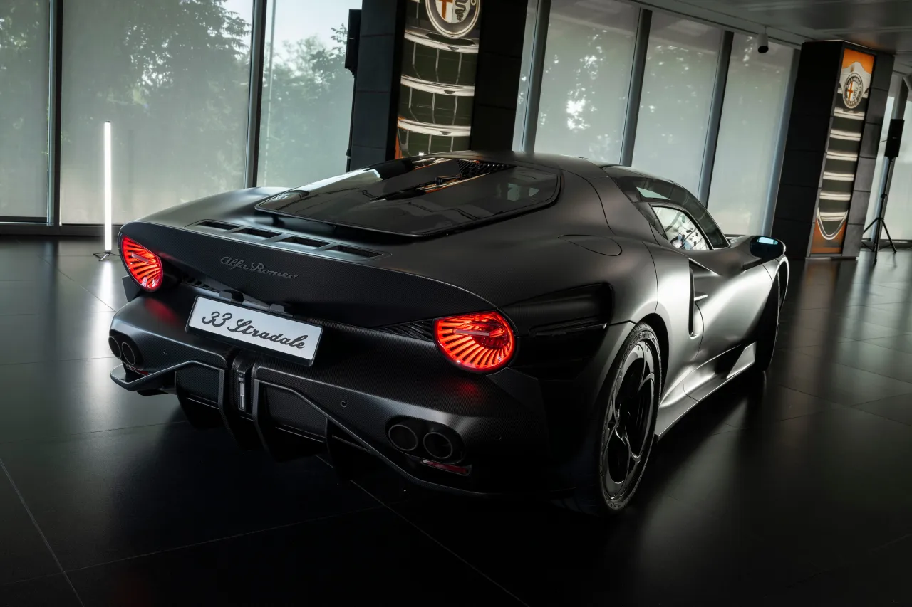 Чёрный Alfa Romeo 33 Stradale представлен в помещении, подчёркивающий заднее освещение и обтекаемый аэродинамический корпус.