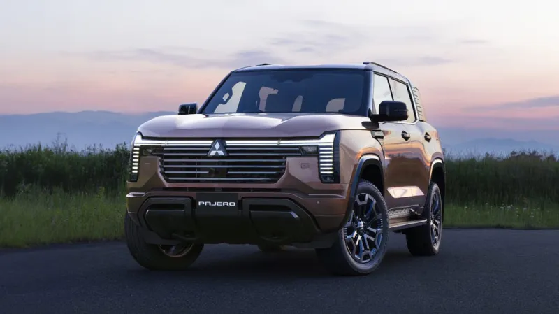 Новый Mitsubishi Pajero на дороге с величественными горами и закатным солнцем
