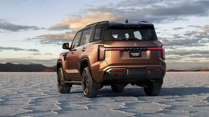 Коричневый автомобиль повышенной проходимости на фоне соляного озера и облачного неба.