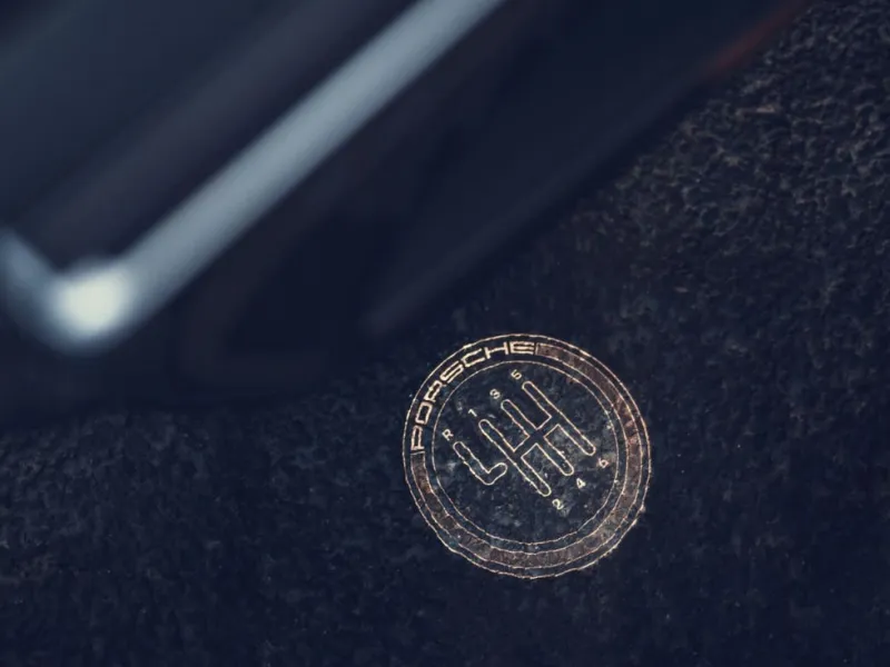 Porsche gearshift pattern logo on a dark textured surface